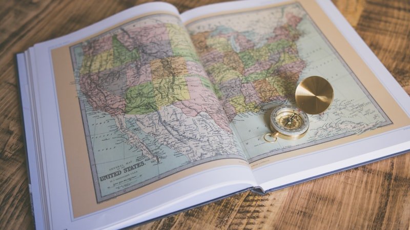 Compass resting on an open map book symbolizing navigation before GPS